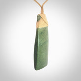Hand carved from a lovely piece of local New Zealand Jade. We have suspended this from a 3-plait beige cord which can be adjusted with a couple of slip knots and beige binding.